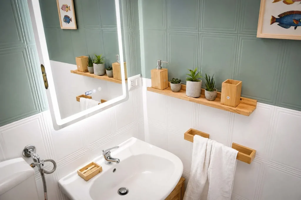 Lavandino bianco con specchio a LED illuminato e accessori in legno nel secondo bagno della casa vacanze La Dimora di Arianna a Cariati.