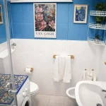 Bagno principale con lavatrice, sanitari e pareti azzurre decorato con quadri di Van Gogh presso la casa vacanze a Cariati.