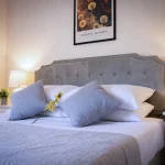 Letto matrimoniale king size allestito con biancheria bianca e cuscini grandi in una casa vacanze in Calabria.