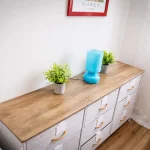Cassettiera moderna in legno chiaro e tessuto con lampada azzurra e piantine decorative nella cameretta della casa vacanze a Cariati.