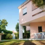 Facciata della casa vacanze rosa La Dimora di Arianna a Cariati con portico attrezzato per mangiare all'aperto e barbecue in muratura.