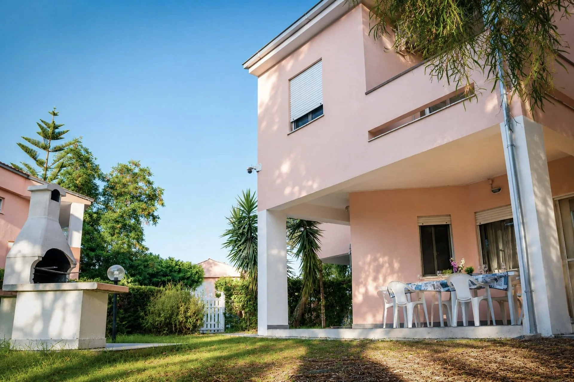 Facciata della casa vacanze rosa La Dimora di Arianna a Cariati con portico attrezzato per mangiare all'aperto e barbecue in muratura.