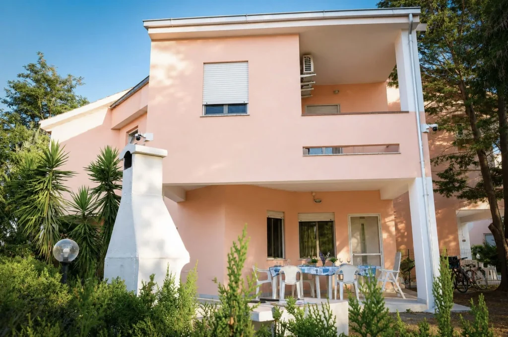 Facciata rosa a due piani della casa vacanze La Dimora di Arianna a Cariati Marina, con portico e barbecue in muratura.