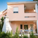Facciata rosa a due piani della casa vacanze La Dimora di Arianna a Cariati Marina, con portico e barbecue in muratura.