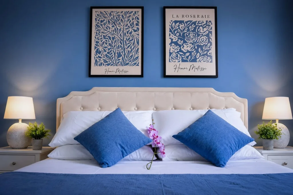 Letto matrimoniale con cuscini blu cobalto, orchidea rosa e quadri di Matisse nella seconda camera a Cariati Marina.