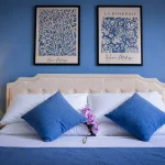 Letto matrimoniale con cuscini blu cobalto, orchidea rosa e quadri di Matisse nella seconda camera a Cariati Marina.