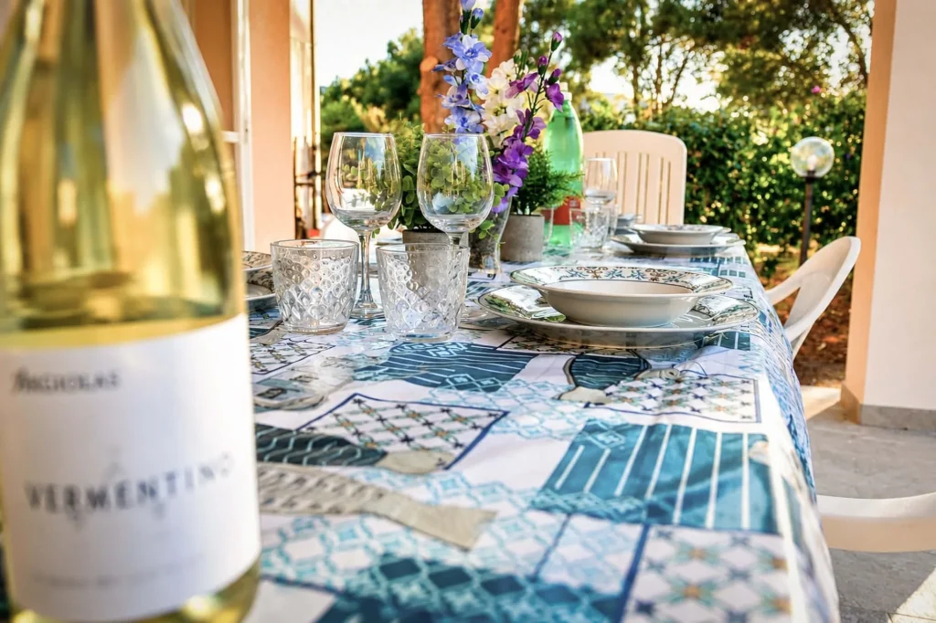 Bottiglia di vino Vermentino in primo piano su tavola apparecchiata all'aperto nel portico della casa vacanze a Cariati.