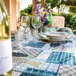 Bottiglia di vino Vermentino in primo piano su tavola apparecchiata all'aperto nel portico della casa vacanze a Cariati.